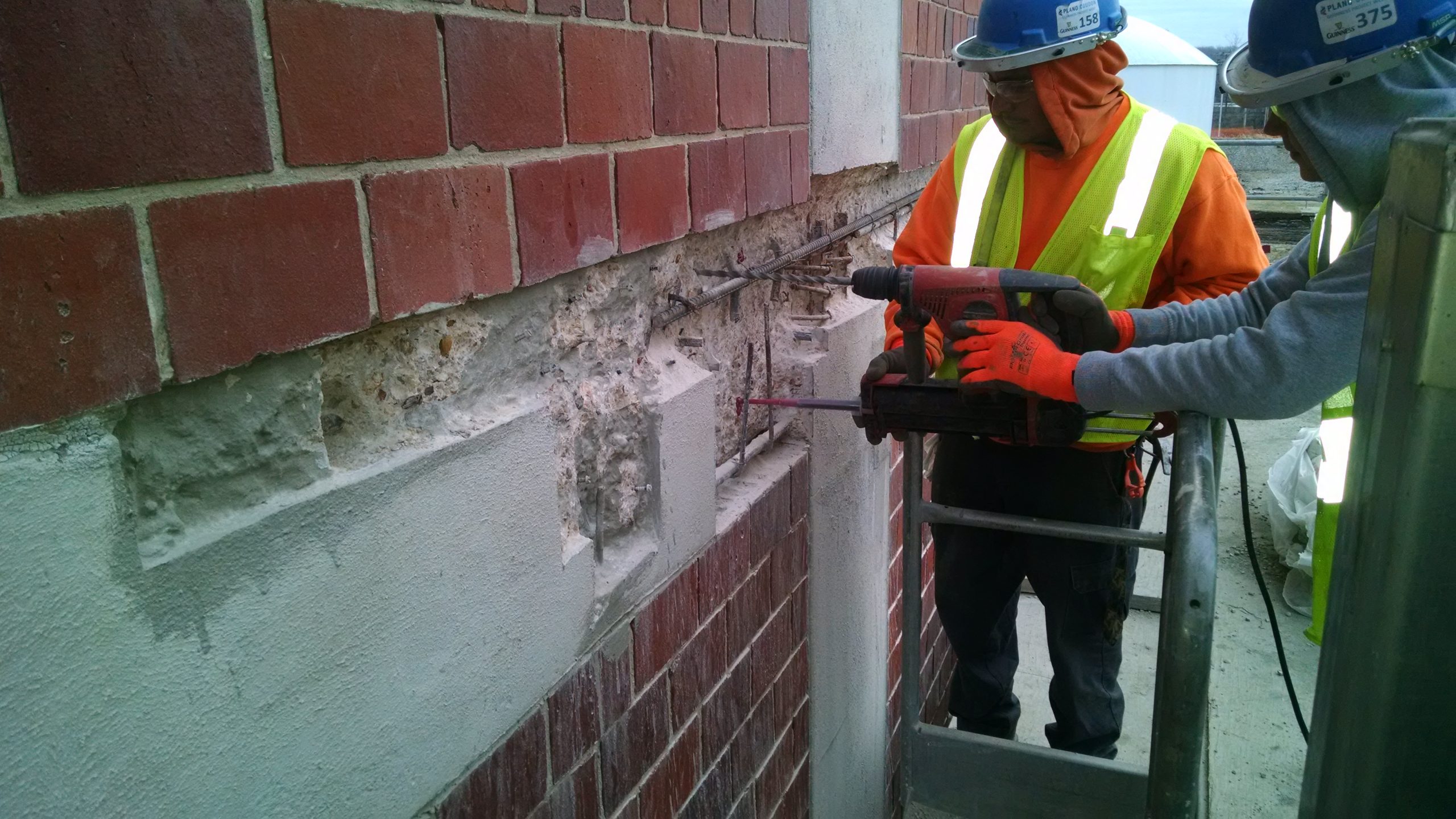 Structural Restoration Service's crew drilling in an exteior building wall